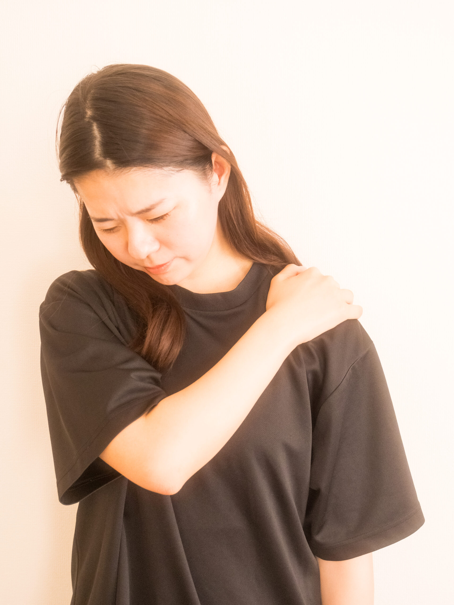 デスクワークで肩こりや腰痛に悩む女性